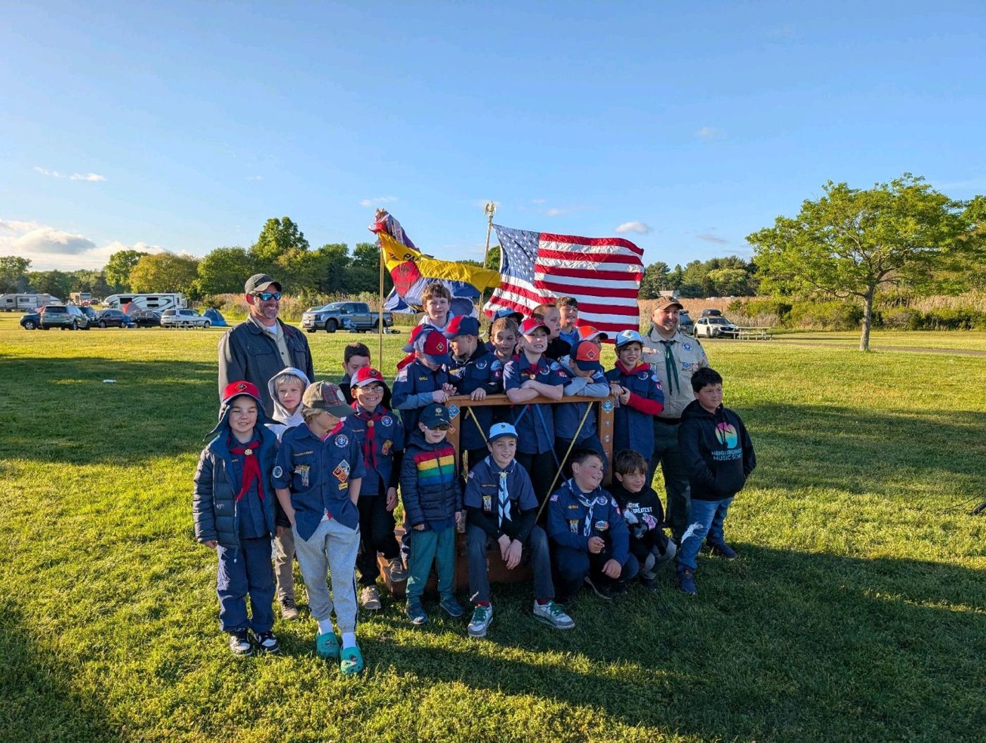 Cub Scouts in uniform posing with the American flag at the spring campout