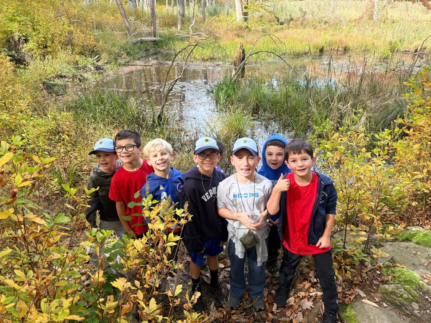 Bear den Scouts smiling by a pond in fall colors