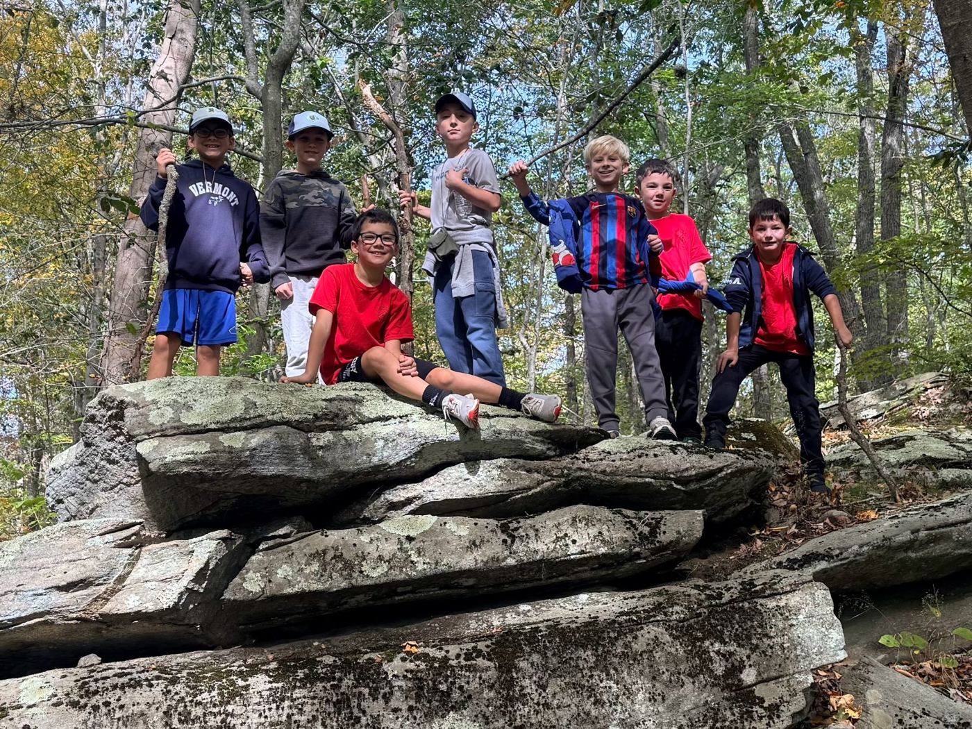 Bear den Scouts standing on large rocks on a fall hike