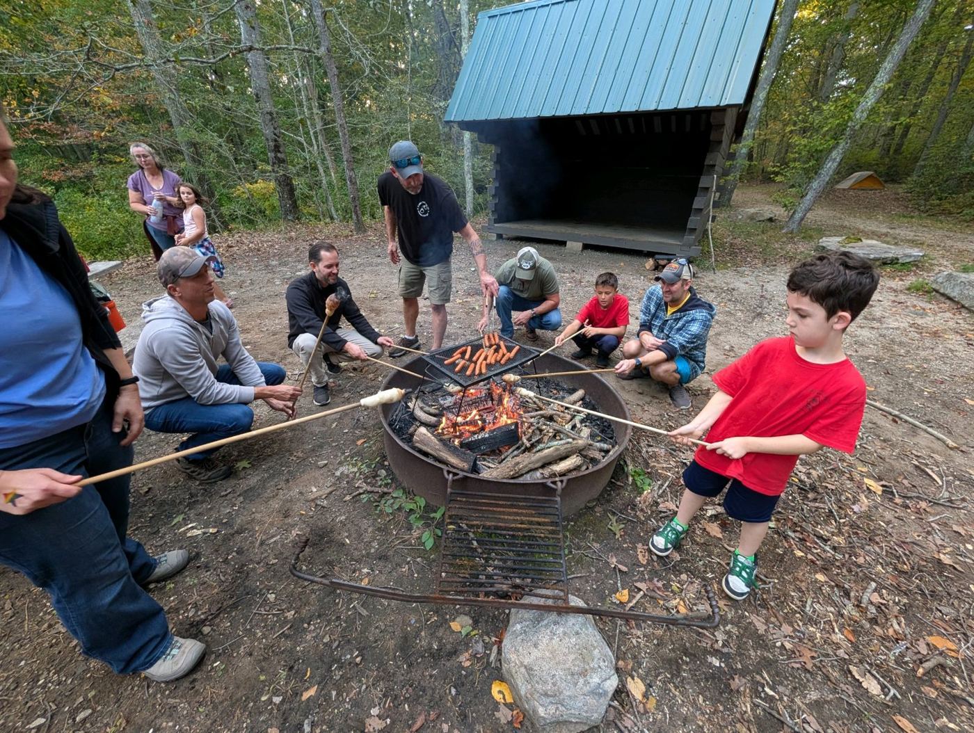 Parents and Scouts cooking around a fire pit at camp