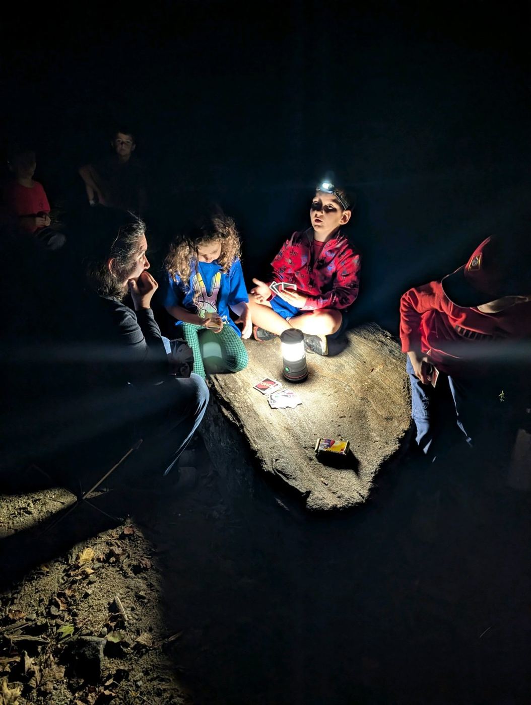 Scouts gathered around a lantern at night at camp