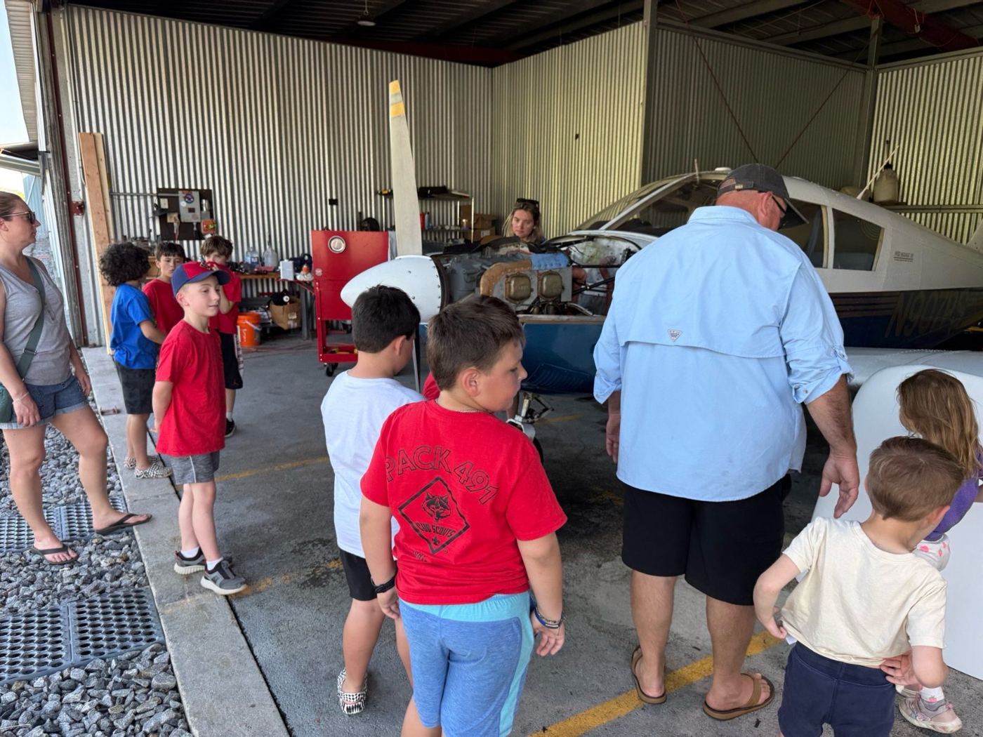Scouts and parents listening to a pilot in an airplane hangar