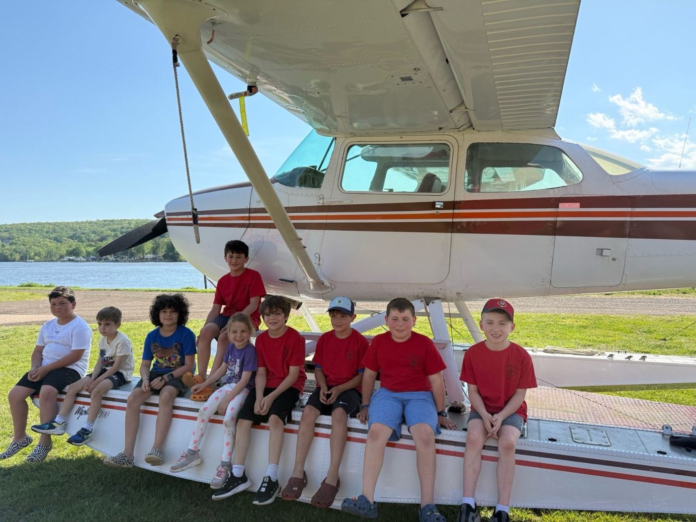 Cub Scouts sitting on the wing of a small airplane