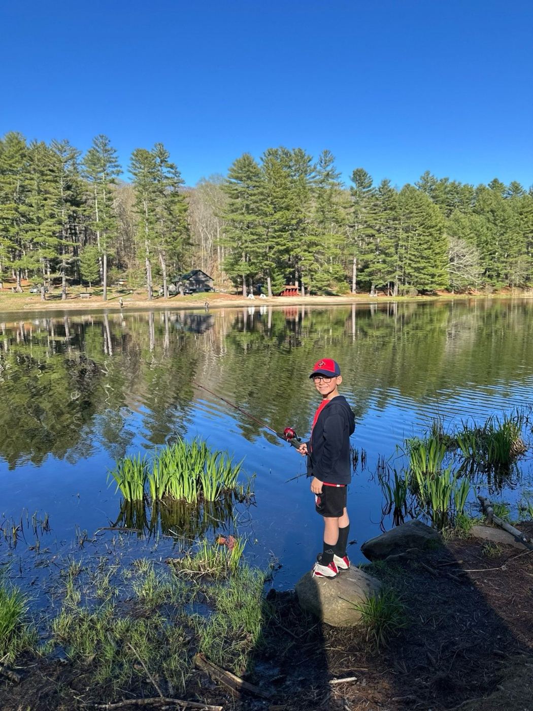 A Wolf Scout fishing from the shore of a calm pond